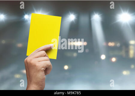 Hand des Schiedsrichters mit gelben Karte auf Fußball-Stadion bei Match Stockfoto