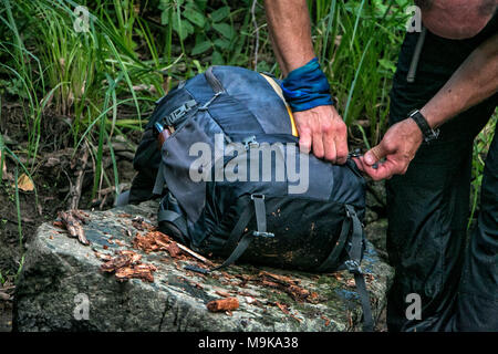 Ein Mann ist Befestigung seinen Rucksack auf dem großen Fluss Stein. Konzept der allein zu sein und in der Wüste verloren. Mann vs wild. Stockfoto