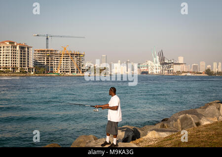 Mann angeln entlang Regierung Wasserstraße in Miami Beach, Florida Stockfoto