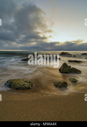 Seascape seidigen Meer mit Steinen gegen eine bunte Himmel bei Sonnenaufgang. Stockfoto