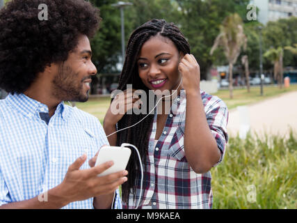 Afrikanische amerikanische Frau genießt Musik mit hipster Freund draußen in der Stadt Stockfoto