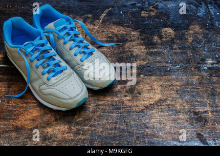 Blick von oben auf die Blaue Schuhe mit alten hölzernen Tafel Hintergrund. Moody Schuhe Fotografie. Stockfoto