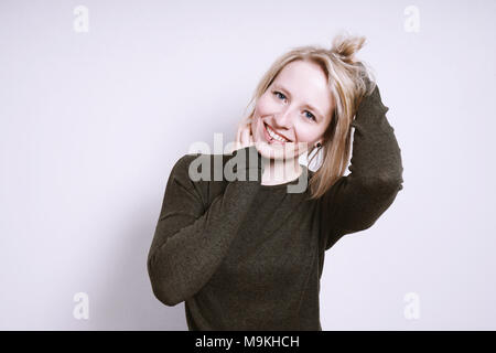 Glückliche junge lächelnde Frau mit Händen in Haar Stockfoto