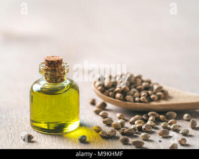 Hanfsamen und Hanföl auf braune Holztisch. Hanf samen in Löffel aus Holz und Hanf ätherisches Öl in kleinen Fläschchen. Kopieren Sie Platz für Text Stockfoto