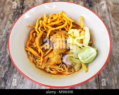 Beliebte Speise von Khao Soi Curry Suppe-würziger Kokosnuss Creme Curry Suppe mit Ei Nudeln, Huhn Drumstick und eingelegtes Gemüse. Stockfoto