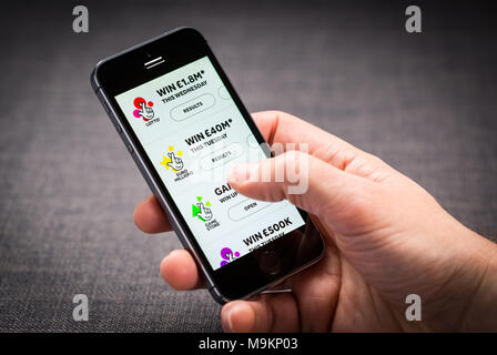 Ein Mann mit der Nationalen Lotterie App auf dem iPhone Stockfoto