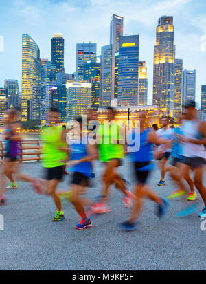 Gruppe von Läufern auf Singapur Kai in der Dämmerung, Singapore Downtown im Hintergrund Stockfoto