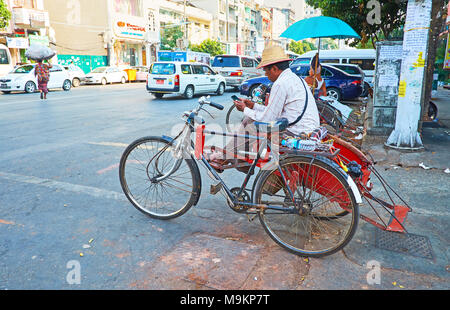 YANGON, MYANMAR - Februar 14, 2018: Die trishaw Fahrer ruht und wartet die Clients an der Straße in Chinatown (Tayoke Tan), am 14. Februar in Yangon. Stockfoto