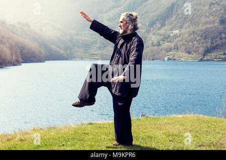 Reife Männer üben von Tai Chi Disziplin im Freien in einem See Park an einem Wintertag Stockfoto