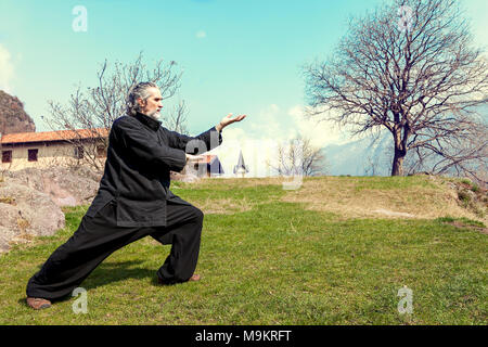 Reife Männer üben von Tai Chi Disziplin im Freien in einem See Park an einem Wintertag Stockfoto