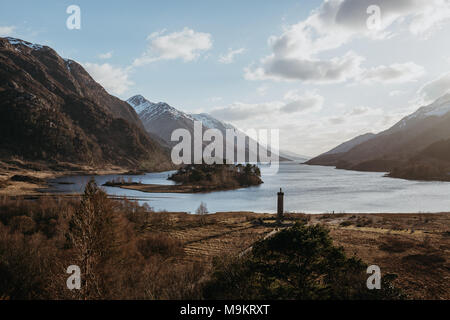 Blick auf das glenfinnan Monument, Loch Shiel und schottische Landschaft in der Nähe von Glenfinnan, Inverness-shire, Schottland, auf einem kalten Frühjahr sonnigen Tag. Stockfoto