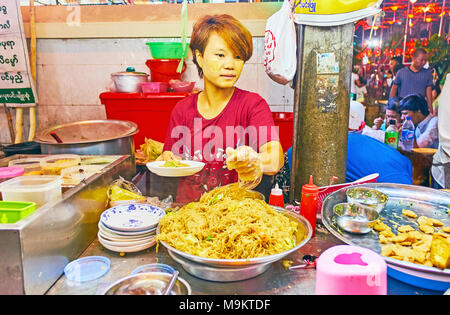 YANGON, MYANMAR - Februar 14, 2018: Der junge Koch mixe Nudeln mit Gemüse in der Open-air-Küche von Street Cafe, an der Guanyin Gumiao T entfernt Stockfoto