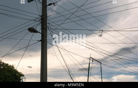 Mehrere Stromleitungen auf der gleichen Post in Holguin, Kuba. Eine gebrochene hausgemachte Kite gesehen werden kann, die von einer von Ihnen. Stockfoto