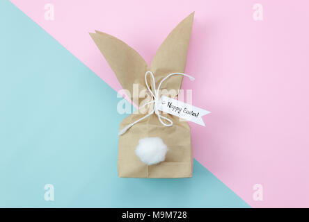 Tabelle Ansicht von oben geschossen von Anordnung Dekorationen Frohe Ostern Urlaub Hintergrund Konzept. Flach schöne bunny Ohr Papiertüte für Geschenk auf modernen Rosa Stockfoto