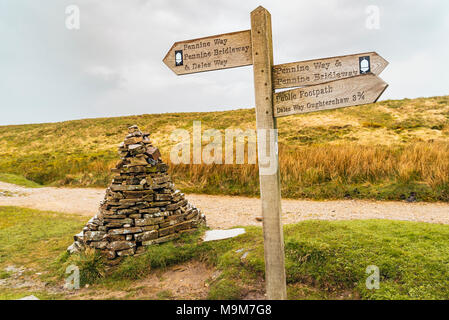 Hinweisschild und Cairn an der Kreuzung von mehreren Wander- und Radwege auf der Cam Hohe Straße zwischen Ribblesdale und Langstrothdale, Yorkshire Stockfoto