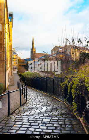 Pfad vorbei an neuen Gehäuse neben der Lancaster Canal in Lancaster England, mit Blick auf das weiße Kreuz Pub und Saint Peter's RC-Kathedrale Stockfoto