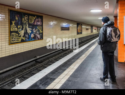 Belin-Mitte, Oranienburger S-Bahn station Interieur mit cremefarbenen Fliesen, Wände und farbenfrohen Kunstwerken Senior älteren männlichen wartet auf der Plattform. Stockfoto