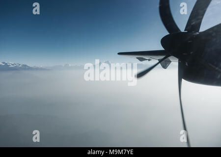 Der Himalaya als von einem Propeller Flugzeug in Nepal gesehen. Schicht von Wolken unter dem Berggipfel. Stockfoto