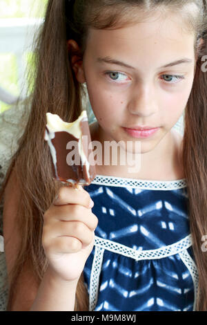 Junge Mädchen/Kind an einer Schokolade Eis zum Schmelzen in der Hand starrte. Stockfoto