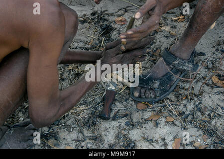 San Stamm Buschmänner, auch bekannt als der Erste Stamm von Afrika, Feuer machen die traditionelle Art und Weise in die umliegende Buschland in Namibia. Stockfoto