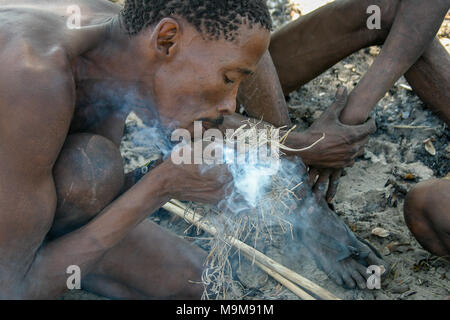 San Stamm Buschmänner, auch bekannt als der Erste Stamm von Afrika, Feuer machen die traditionelle Art und Weise in die umliegende Buschland in Namibia. Stockfoto