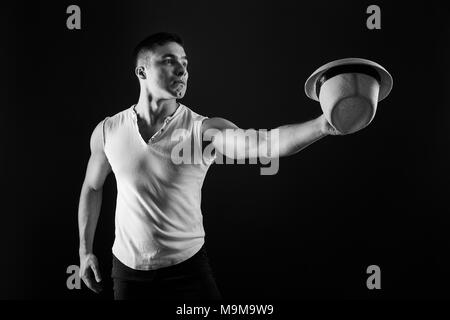 Man Fashion Model, stilvolle junge Mann mit Fedora Hut ständigen posiert, über schwarzen Hintergrund. Schwarz-weiß Foto. Stockfoto