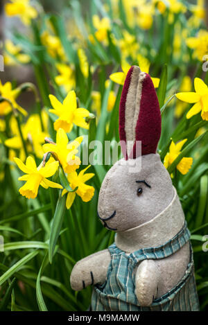 Spielzeug Kaninchen sitzen unter Narzissen, saisonalen Osterhasen. Stockfoto