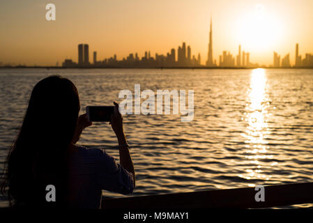 Frau unter Foto von Dubai Panorama bei Sonnenuntergang Stockfoto