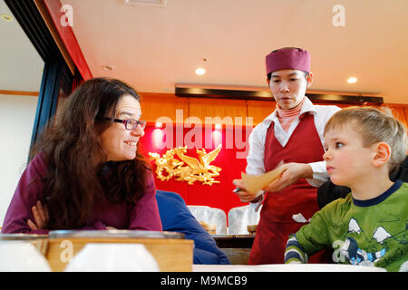 Eine Mutter an ihr fünf Jahre alter Sohn übertragen, wie Dim Sum Spezialitäten werden in einem chinesischen Restaurant serviert Stockfoto