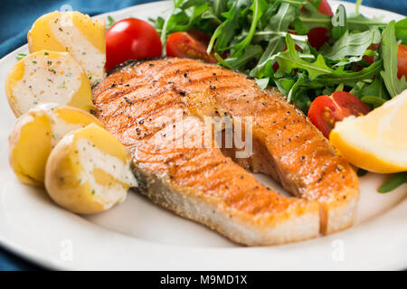 Scheibe der gegrillten Lachs garniert mit gekochten Kartoffeln, Rucola und Cherry Tomaten Salat, Joghurt Sauce mit Kräutern und Zitrone Stockfoto