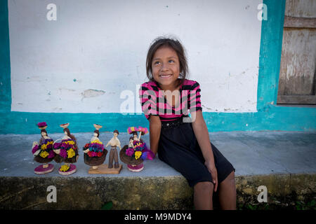 Junge Maya Mädchen lächeln, da sie verkauft ihre Puppen auf den Stufen ihrer Homel in Guatemala Stockfoto