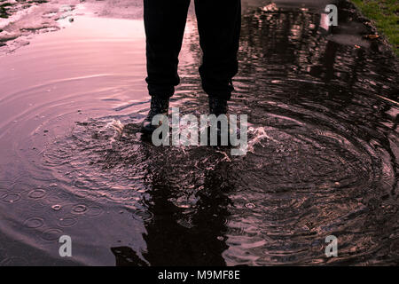 Reflektierende Pfütze, Männer Schritte in einer Pfütze. Goldene Stunde. Park. Stockfoto