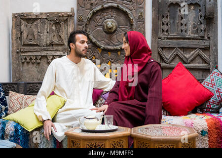Junge muslimische Paare in Beziehung reden und lächeln im traditionellen marokkanischen Haus Stockfoto