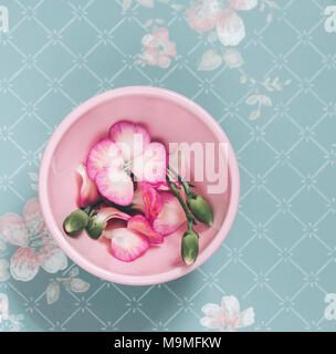 Rosa Schale mit Blumen auf einem verblassten floral background Stockfoto