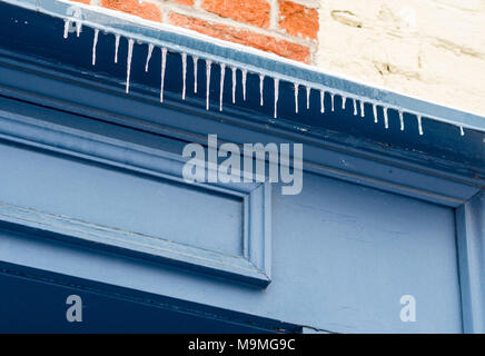 Eiszapfen vor einem Blauen Tor: Eine Reihe von kleinen Eiszapfen hängen über eine Tür ein helles shad Blau auf einem Haus in der Altstadt von Quebec gemalt. Stockfoto