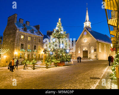 Notre Dame Victorires und Weihnachtsbaum: Die kleine Kirche in der touristischen Abschnitt des unteren Quebec mit einem großen Weihnachtsbaum auf dem Platz beleuchtet. Touristen beobachten und wandern. Stockfoto