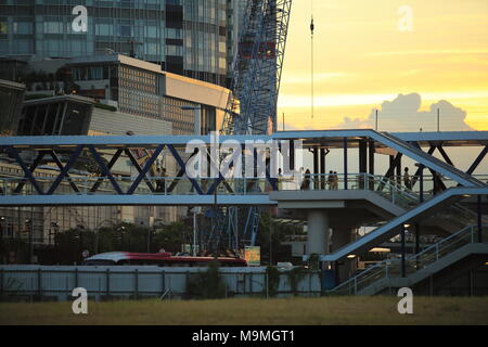 Die Menschen gehen durch die langen fußgängerbrücke an der Anlegestelle der Fähre hinter der IFC International Finance Center in Central, Hong Kong bei Sonnenuntergang Stockfoto