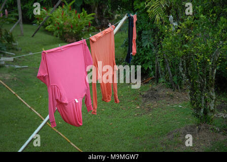 Orange und Rosa tops hängend auf der Wäscheleine im Garten in Suva, Fidschi. Stockfoto