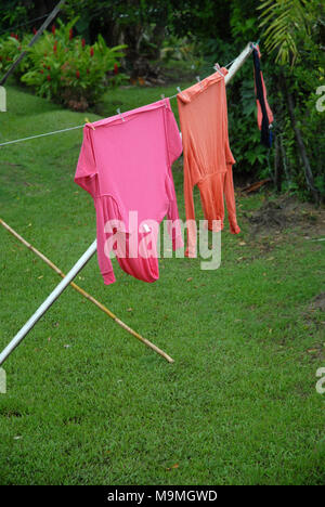 Orange und Rosa tops hängend auf der Wäscheleine im Garten in Suva, Fidschi. Stockfoto