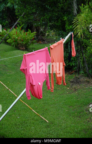 Orange und Rosa tops hängend auf der Wäscheleine im Garten in Suva, Fidschi. Stockfoto