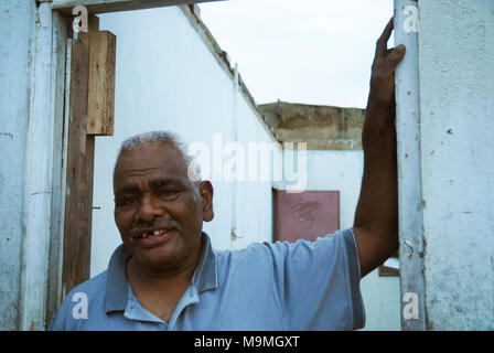 Alter Mann außerhalb seines beschädigten Hauses, Suva, Fidschi. Stockfoto