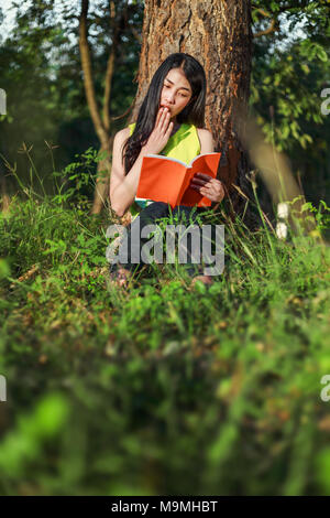 Überrascht Frau mit einem Buch in den Garten Stockfoto