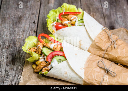 Mexikanische fajitas, Tortilla Wraps mit frischem Gemüse gefüllt und gegrilltem Hühnchen auf rustikalen Holztisch Stockfoto