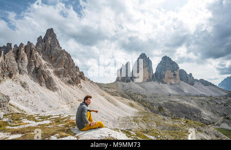 Wanderer sitzt auf Felsen, Gipfel der Paternkofel und Norden Wände der Drei Zinnen von Lavaredo, Sextner Dolomiten, Südtirol Stockfoto