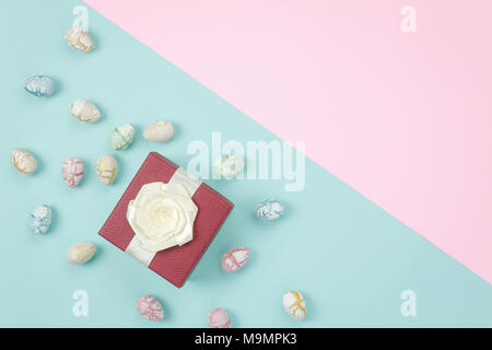 Ansicht von oben geschossen von Anordnung Dekoration Frohe Ostern Urlaub Hintergrund Konzept. Flachbild bunte Ostereier mit Geschenkbox auf modernen Rosa & blau Papier lagen Stockfoto