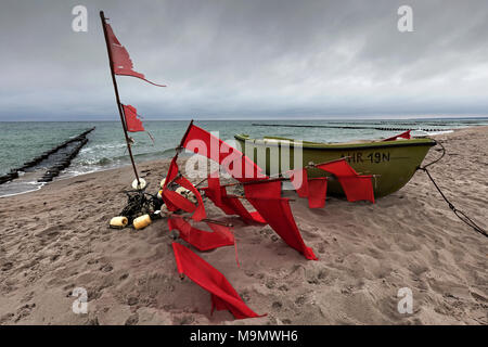 Kleines Fischerboot und Bojen mit roten Fahnen am Strand, Ostseebad Ahrenshoop, Halbinsel Fischland-Darß-Zingst. Stockfoto