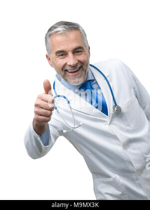 Sicher ein Lächeln auf den Lippen reife Arzt posieren und einen Daumen nach oben Stockfoto