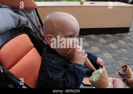 Ein Kind isst viel Eis. Eine Familie an der Eisdiele genießen Eis Kegel. Stockfoto