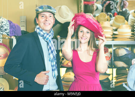 Glückliche junge Frau und Mann die Wahl kleid Hüte im Store. Stockfoto