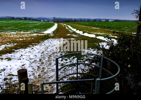 Ein sich küssendes Tor führt ein Fußweg in die Great Ouse Tal zwischen den Feldern der schmelzende Schnee Stockfoto